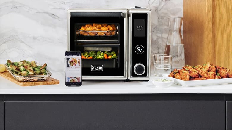 Suvie Kitchen Robot on a counter with cooked sides and the Suvie app